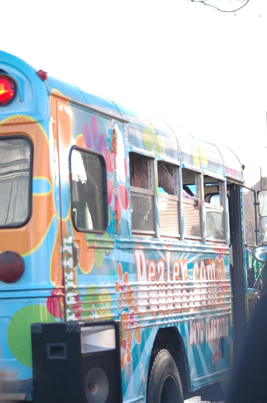 a large colorful bus stopped in traffic at a stoplight