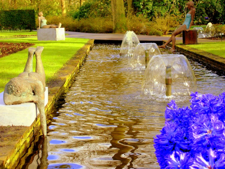 the large fountain is located between purple flowers