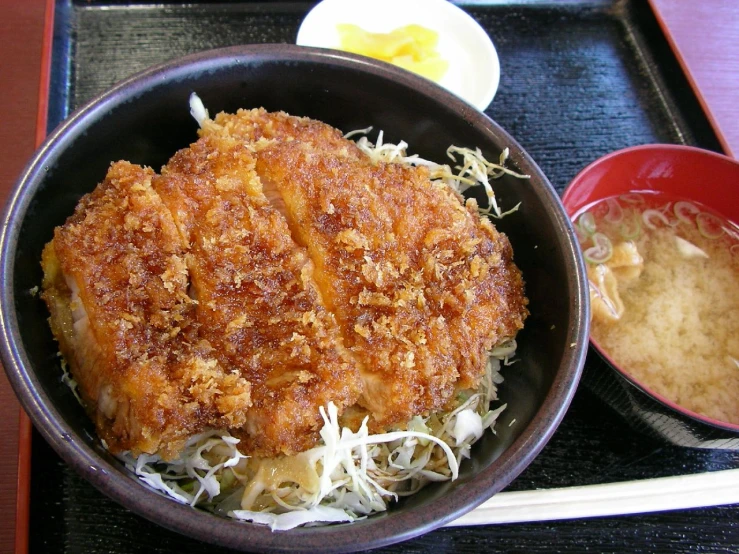 a large portion of fish is in a bowl and with some chopsticks next to it
