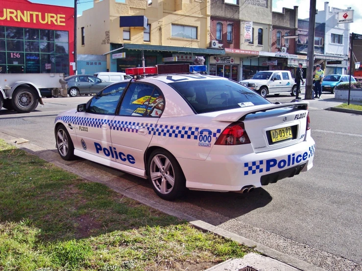 a police car sits parked at a curb next to a street