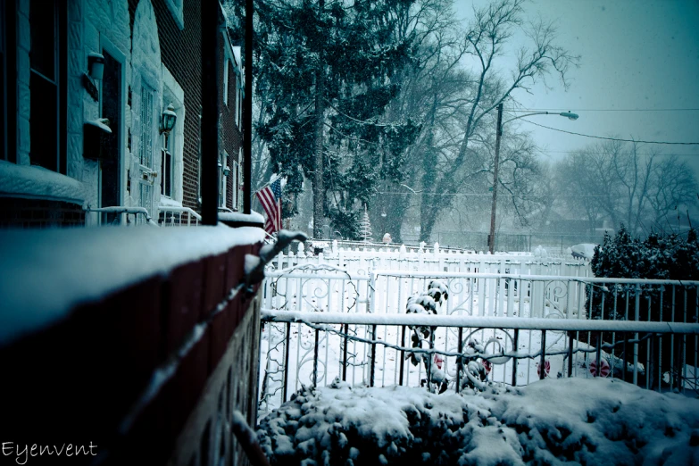 an american flag is in the snow, along with a fence