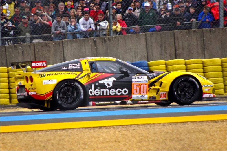 a yellow car with red stripes on a track