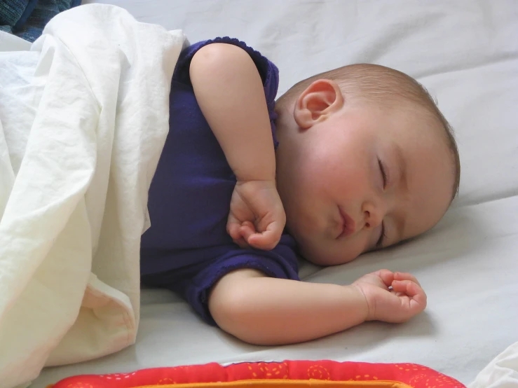 a close up of a child sleeping on a bed