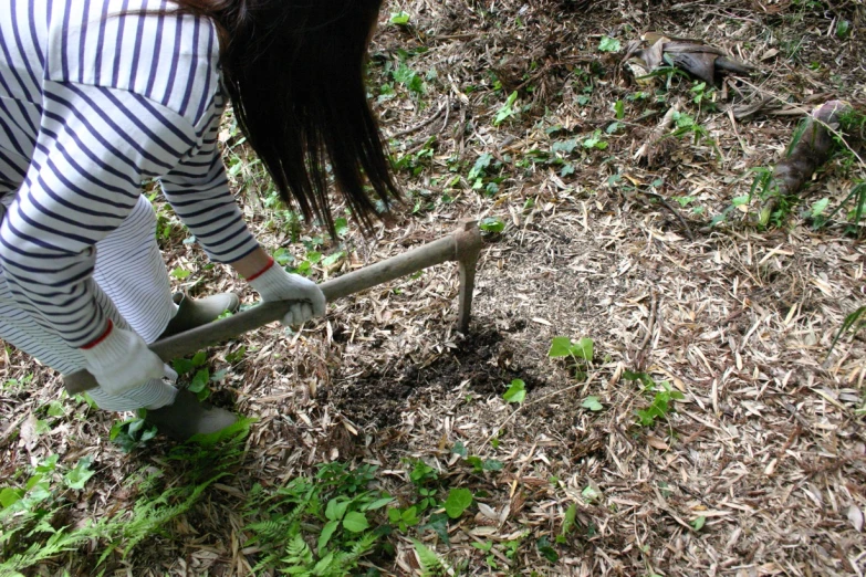  in striped clothes digging up dirt with a small metal shovel