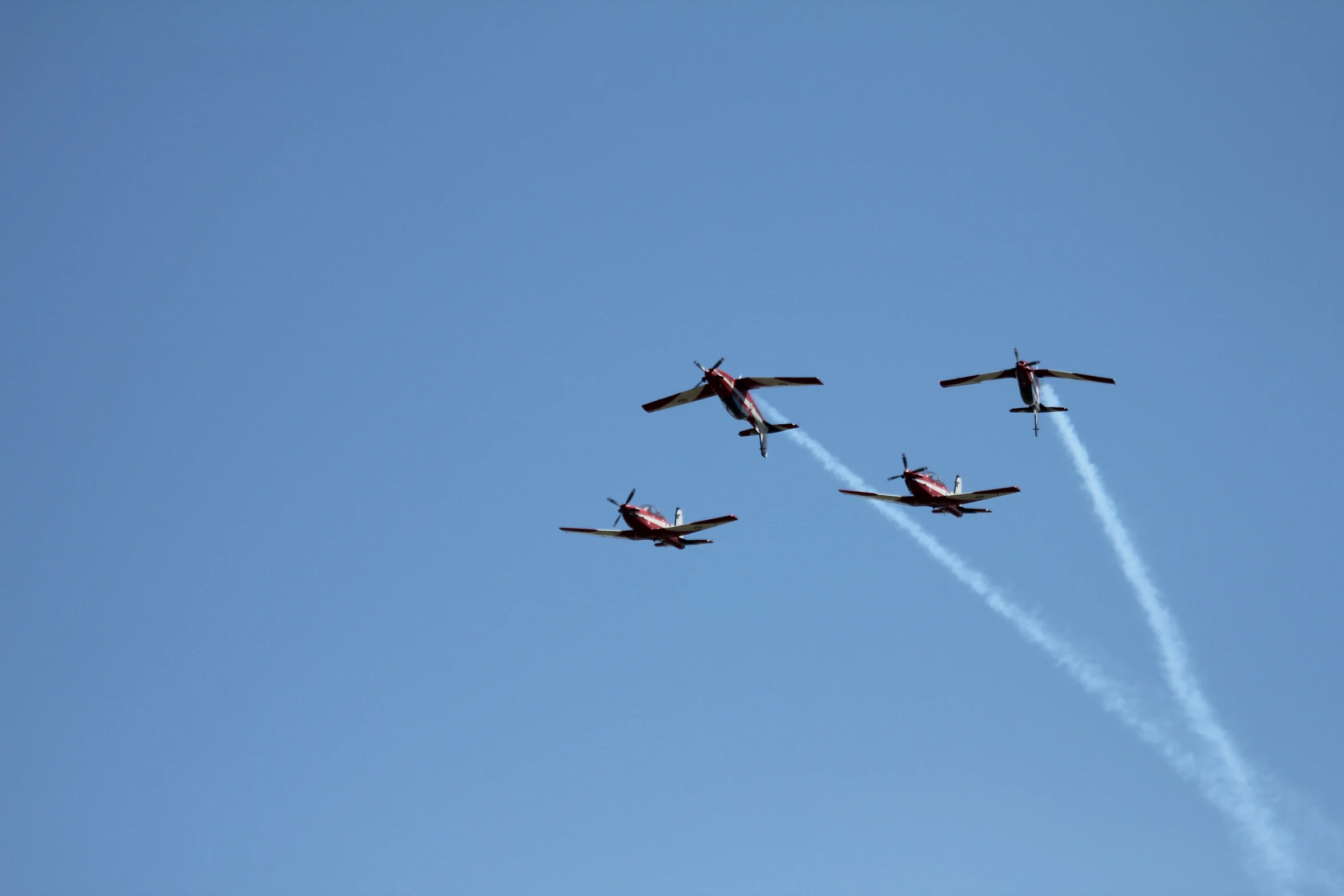 four airplanes flying in the sky leaving smoke trails