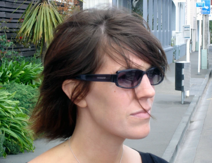 a young woman wearing sunglasses stares off into the distance