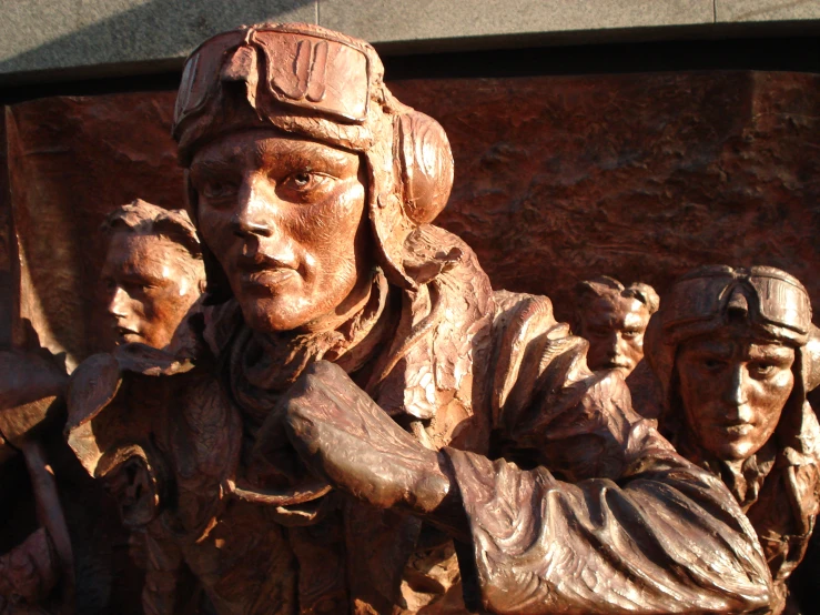 a statue of a man, three other people, holds soing in his hands