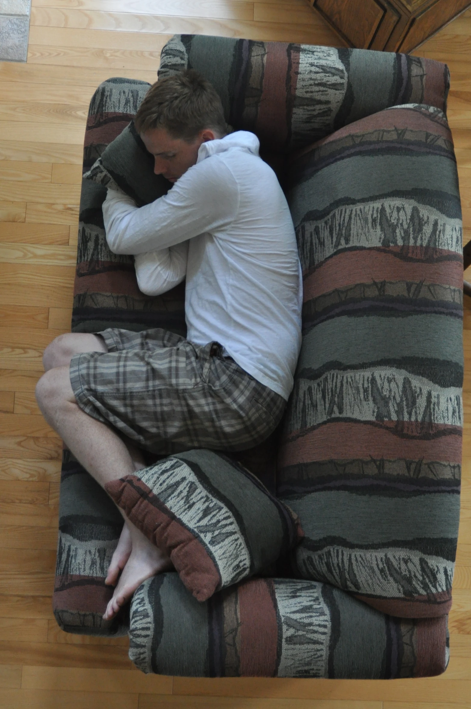 the man is laying on the striped couch with his head propped up