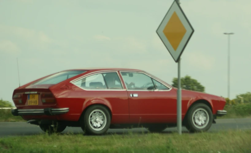 red ford mustang sitting in a field near a traffic sign