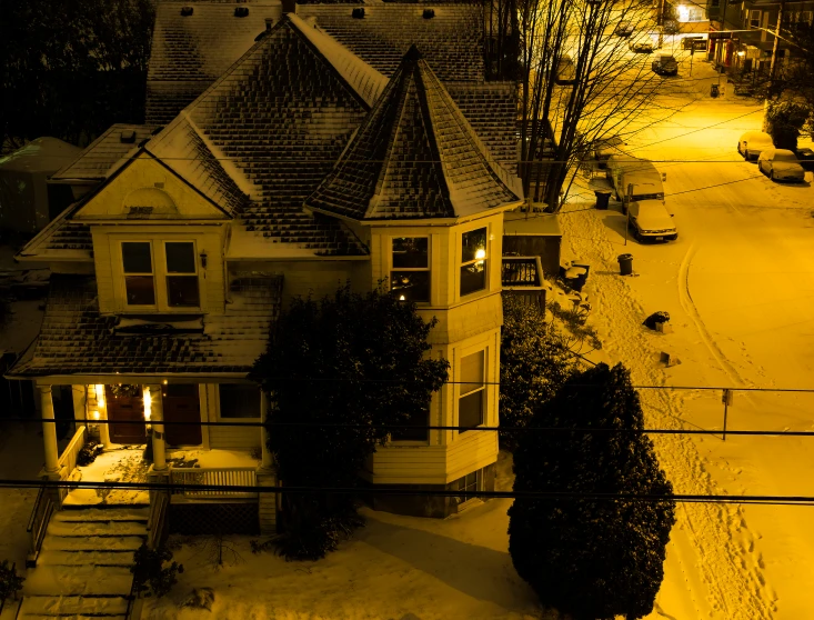 a house covered in snow and some cars outside