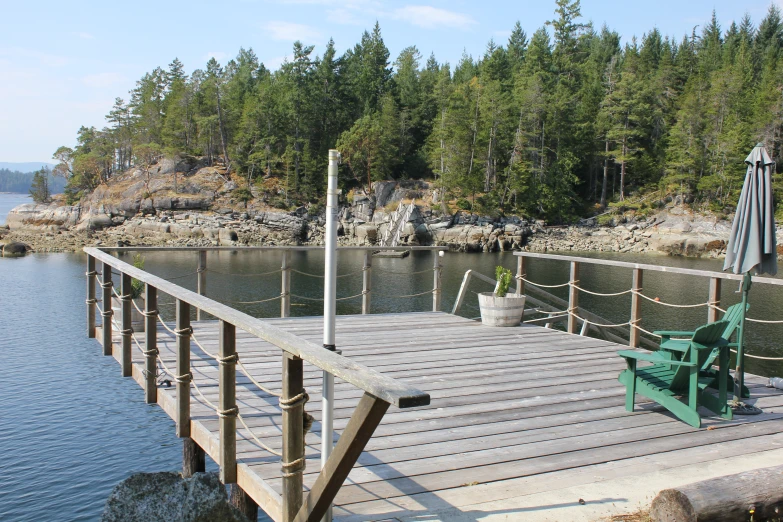 a large wooden dock over water with chairs next to it