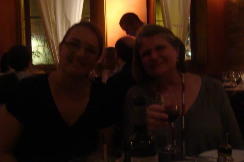 two women sitting at a table with wine glasses