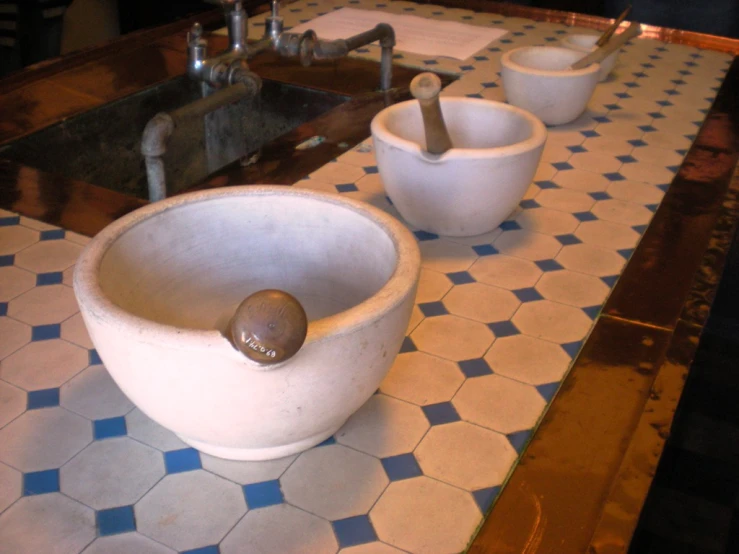 this po shows a bowl, cups and spoons on the counter top