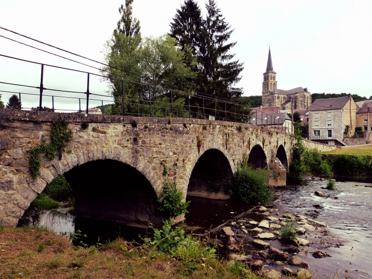 an old bridge with a tower rises above the river