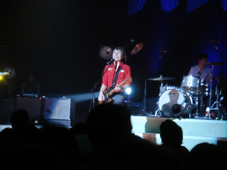 two men are playing guitar on stage while an audience watches