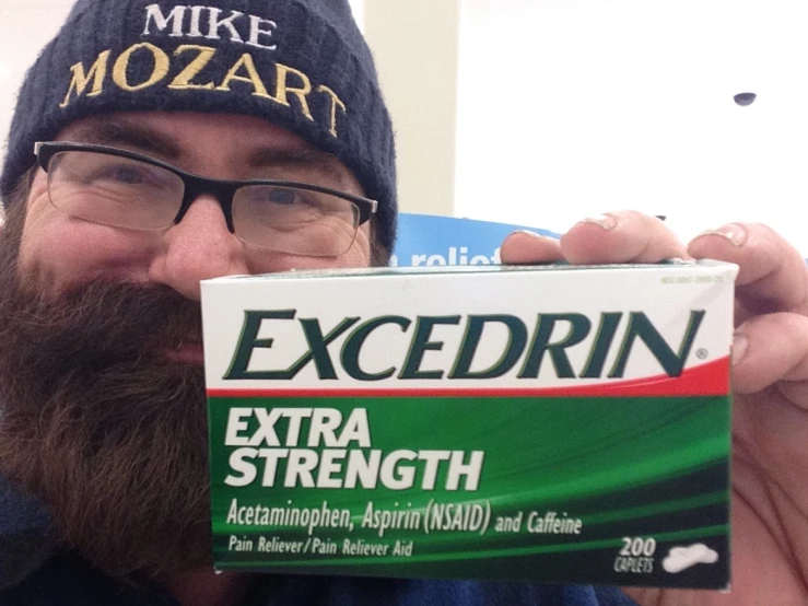 a man with a beard holds up an excedrin box