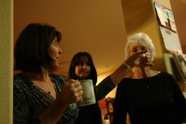 two women with coffee cups talking in front of a mirror