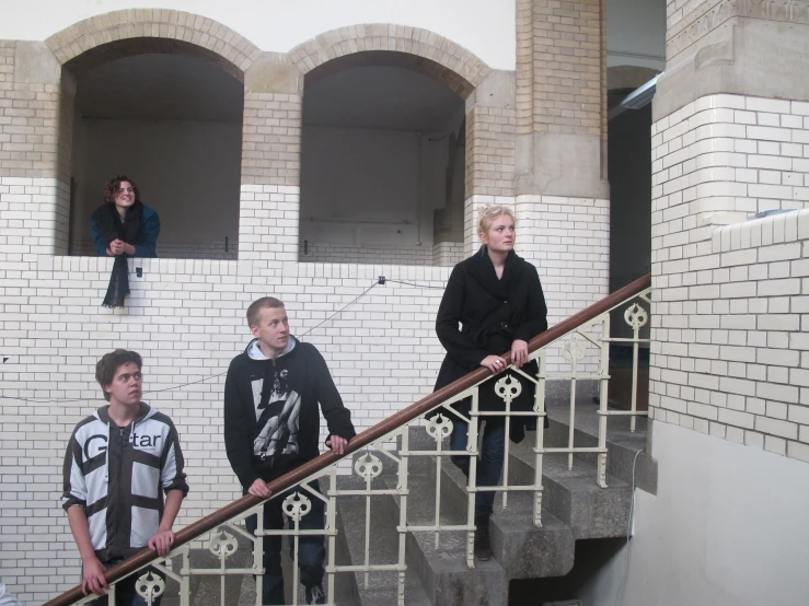 four people are standing on the railing of a staircase