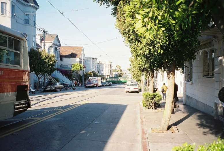 the street is lined with cars, buses and buildings