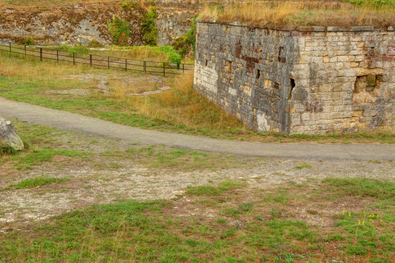 an old brick building sitting next to a lush green field