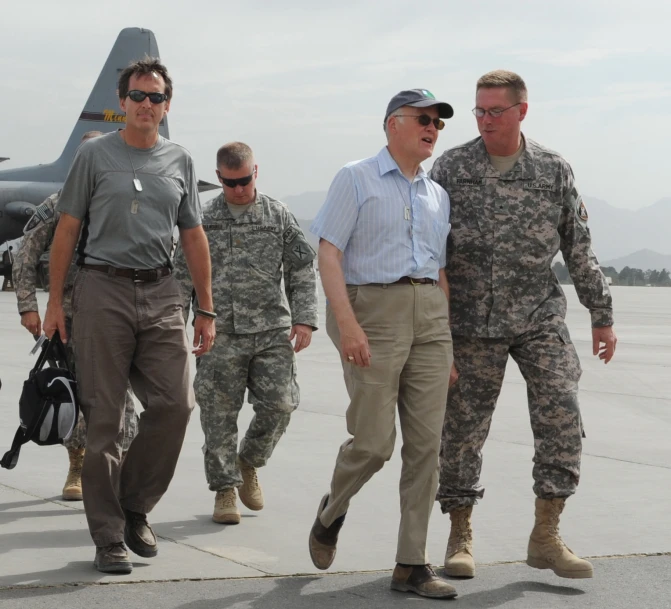 some military men walking around in front of a military plane