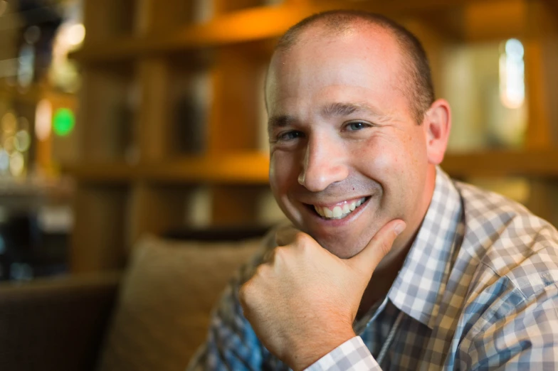 a man smiling while sitting on top of a couch