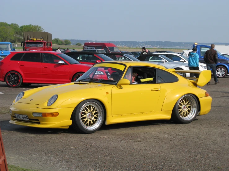 the yellow porsche parked at an event in a parking lot
