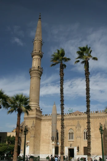 a tall monument stands in front of two palm trees