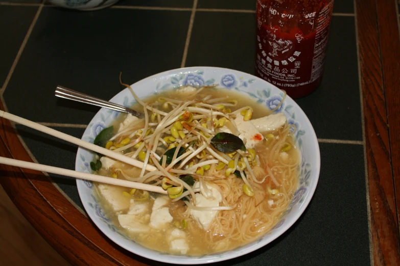 a bowl full of asian noodle soup with chopsticks on the side