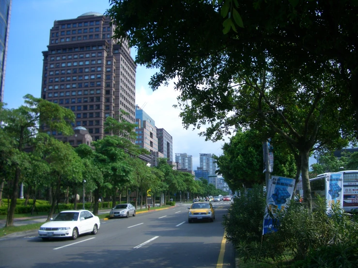 cars driving down a city street next to a tall building