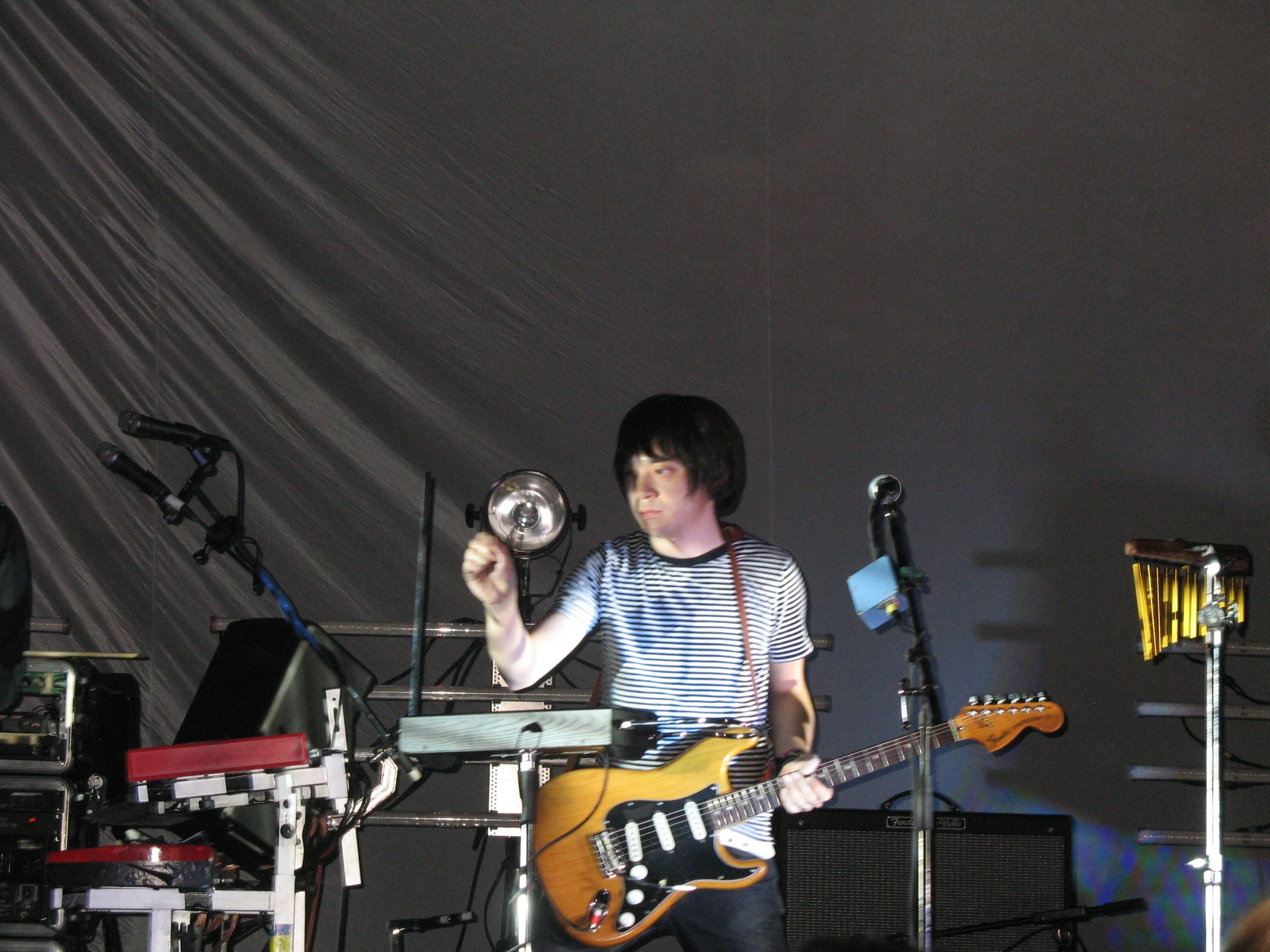a boy standing in front of a microphone holding a guitar