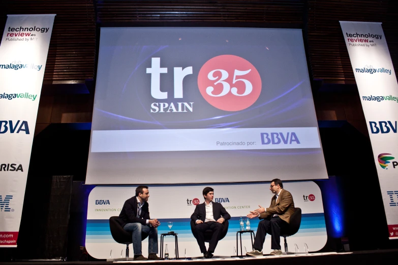 three people sitting on chairs at an event