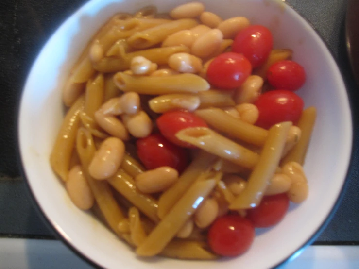 a bowl full of pasta with tomatoes and beans