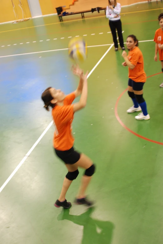 a girl reaches to grab a frisbee in a gym