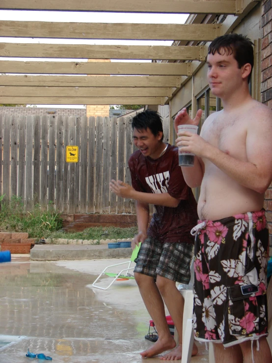 two guys having fun playing with the water in a pool