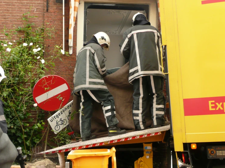 two people in coveralls climbing into a moving truck