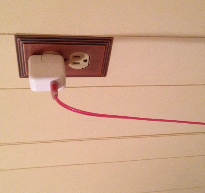 a plug attached to a wall has an electric cord connected