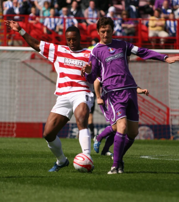 two men on opposing teams playing soccer in a stadium