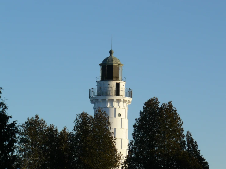 a tall white light house surrounded by trees