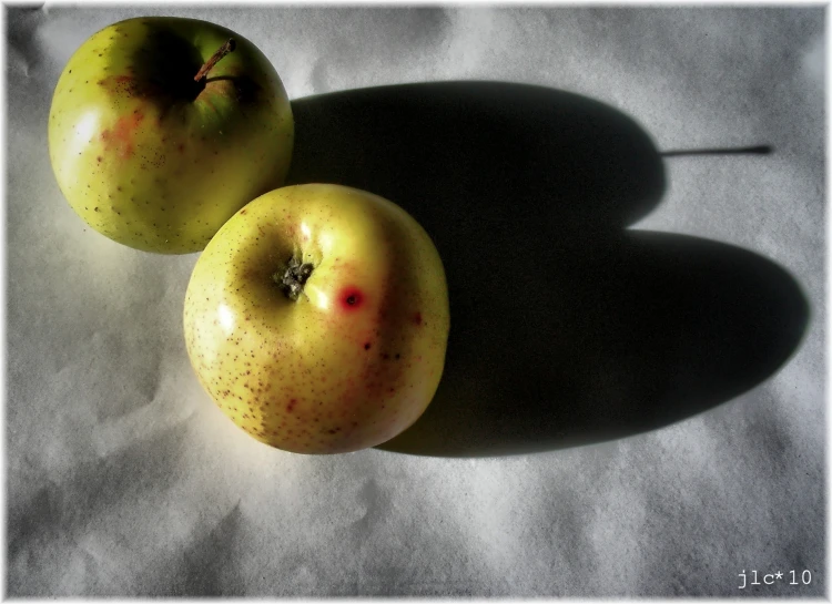 two green apples that are sitting next to each other