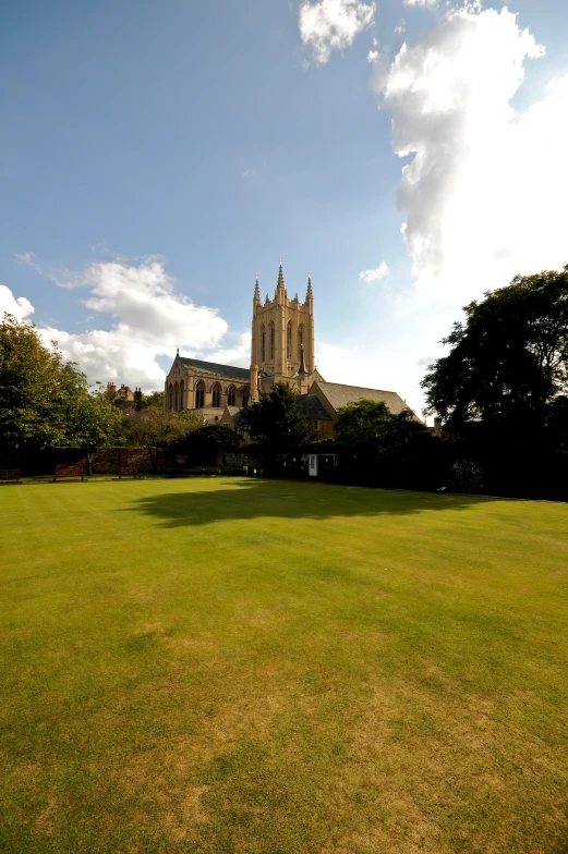 an older church rises above the trees near a grassy area