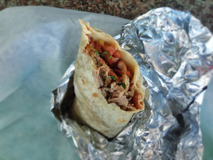 a close up of a burrito wrapped in aluminum foil