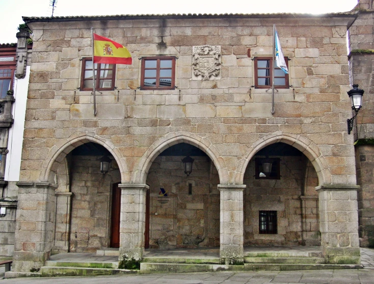 an arched building with two flags hanging on the roof