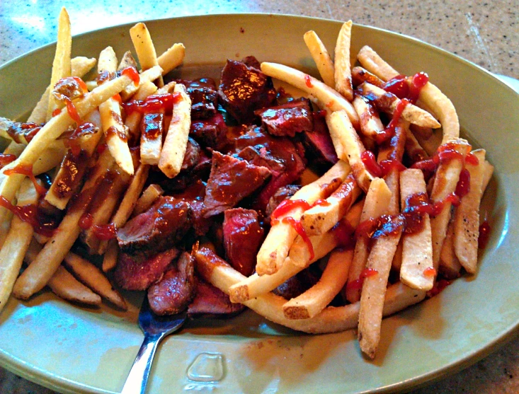 a plate with a meat and fries with some ketchup