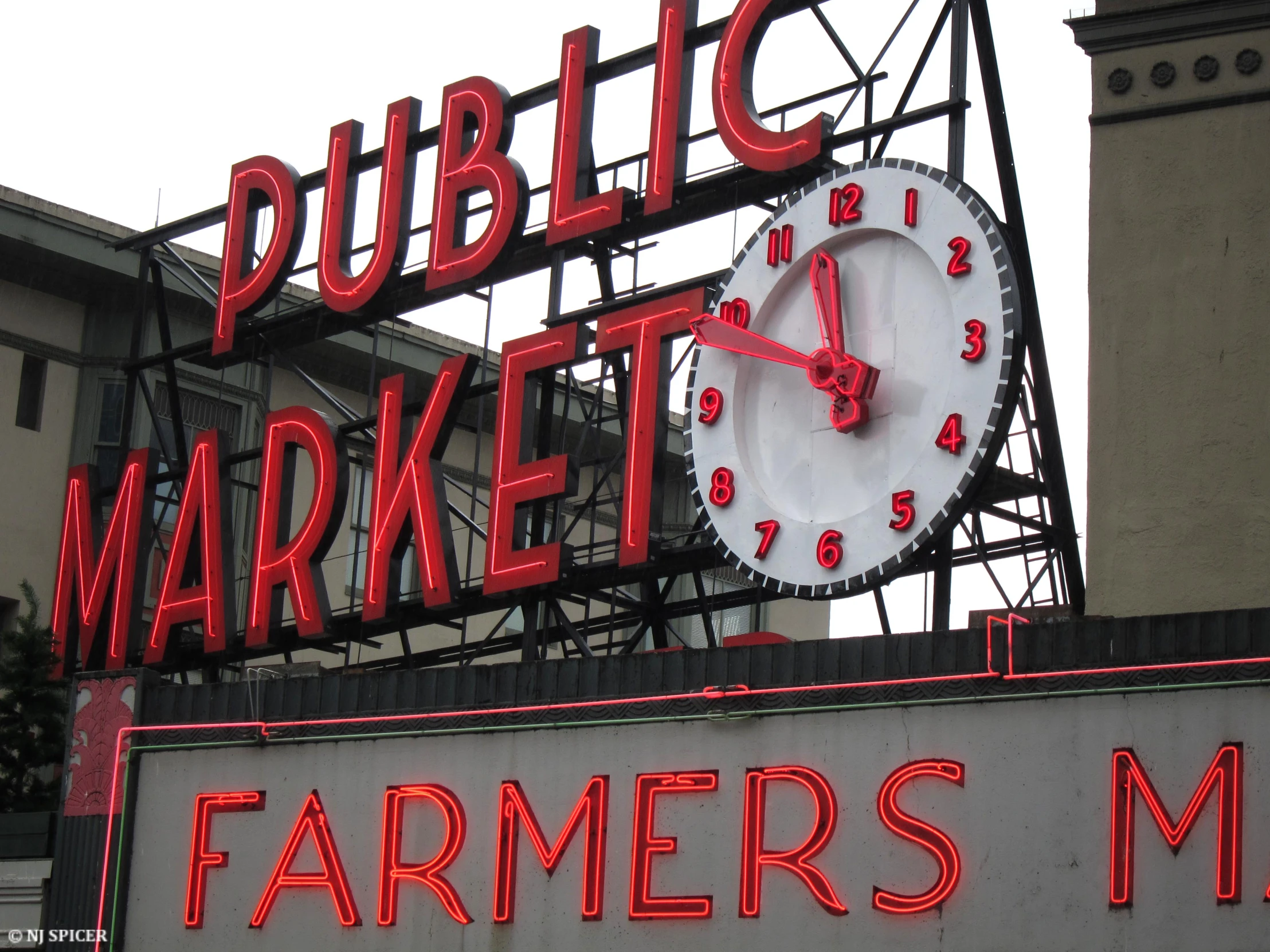 large sign for farmers market and a clock on top of it