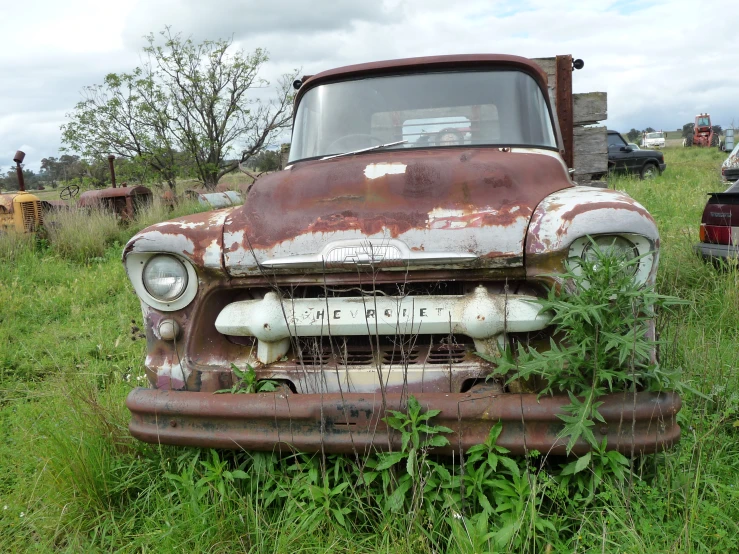 an old rusted out truck is sitting in the middle of a field