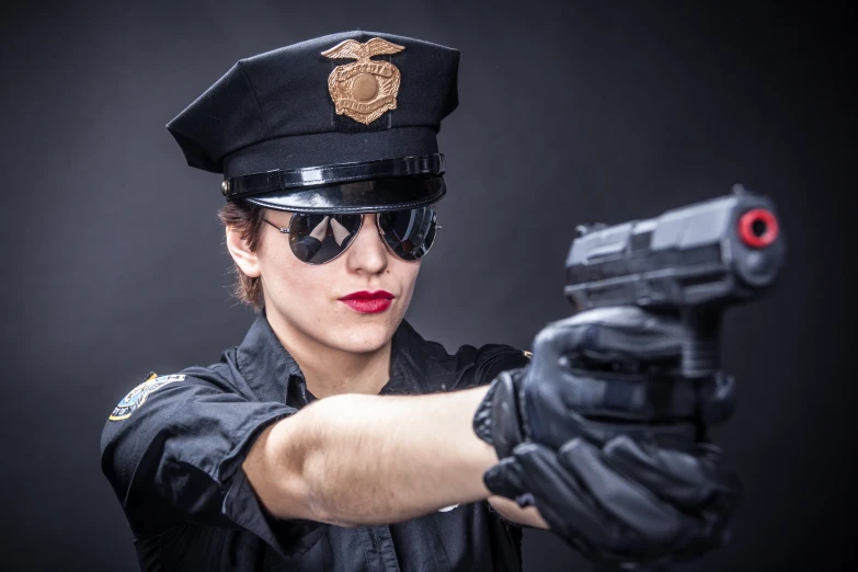 woman in police uniform holding a gun pointing it at the camera