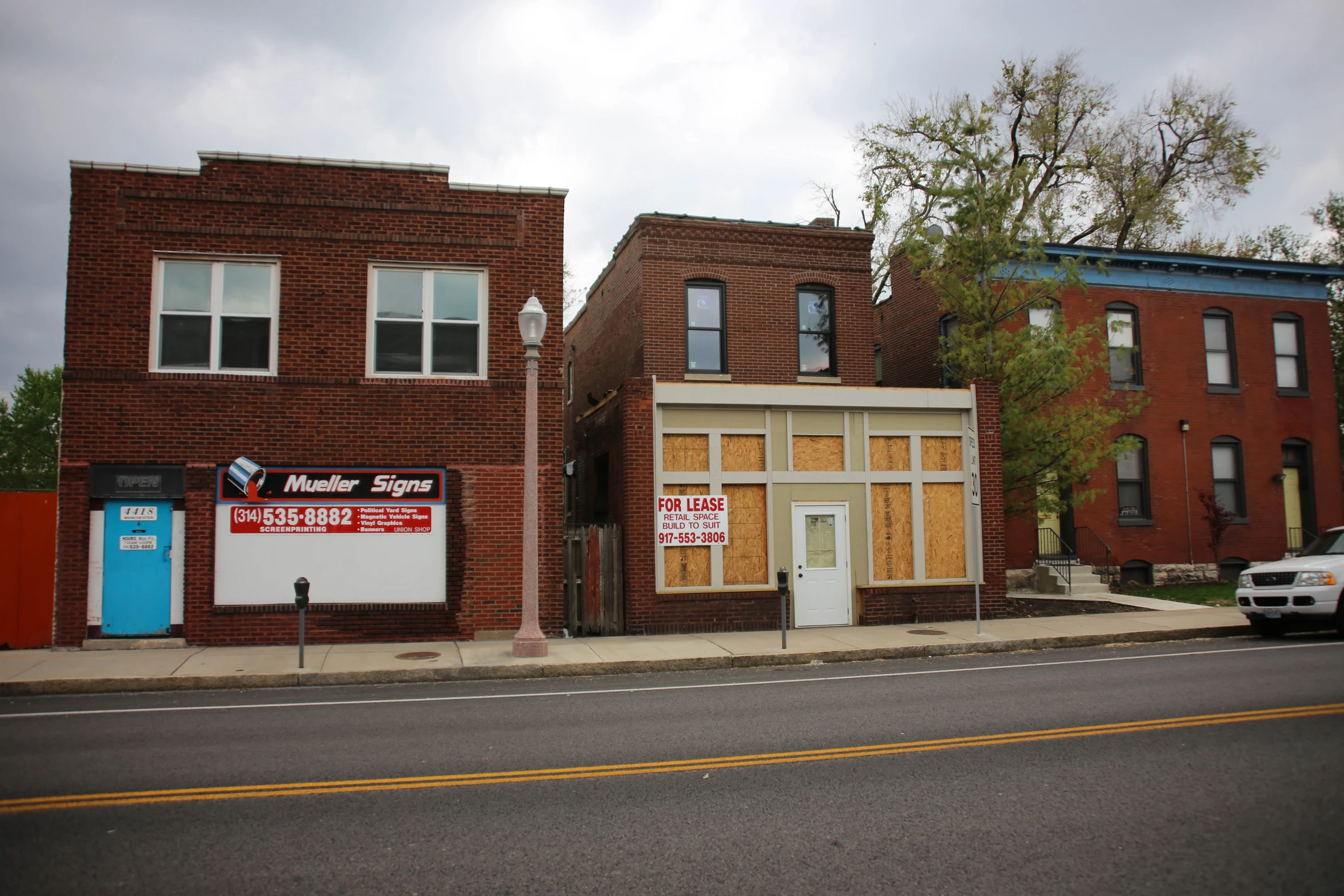 an empty city street lined with boarded up brick buildings