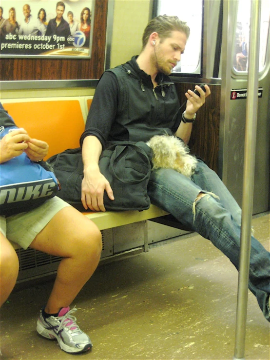 a person sitting on the subway train using a cell phone