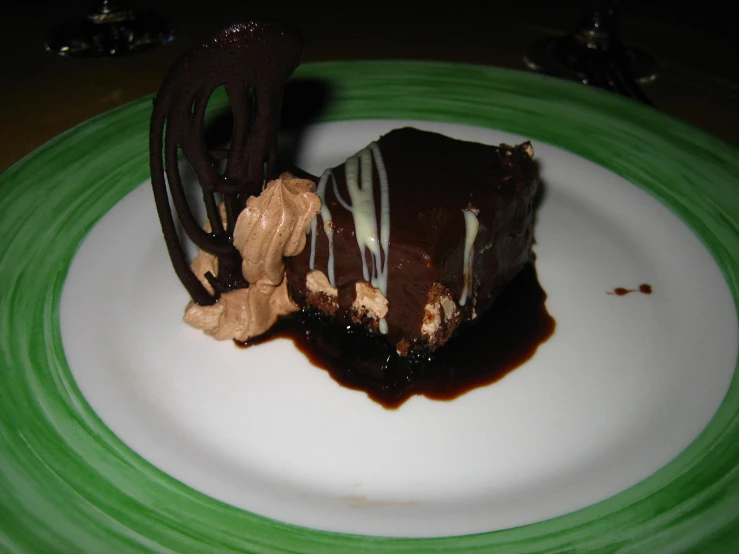 a piece of chocolate dessert and a fork on a green plate